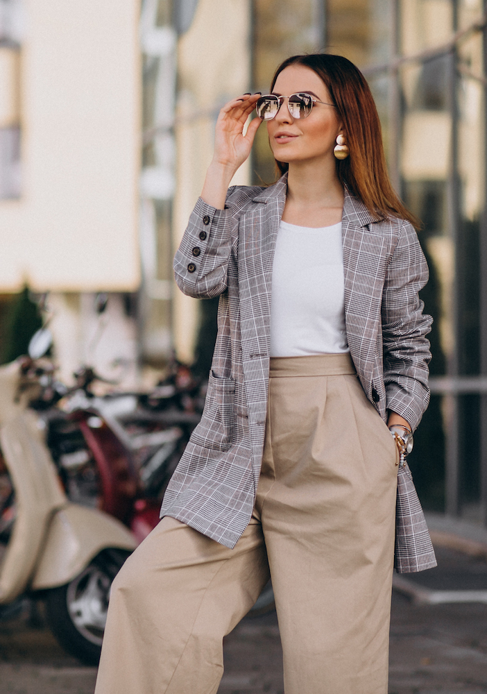 Young woman in suit standing by the scooter