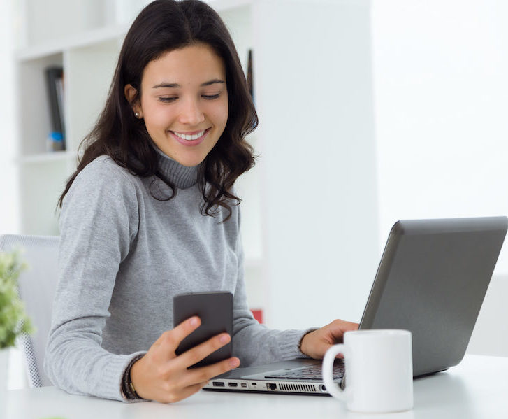 Beautiful young woman using her mobile phone at home.