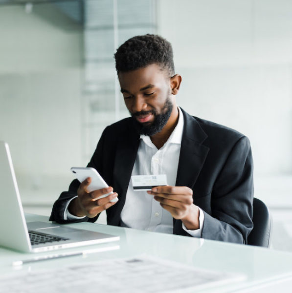 African American man paying with credit card online while making orders via mobile Internet making transaction using mobile bank application.